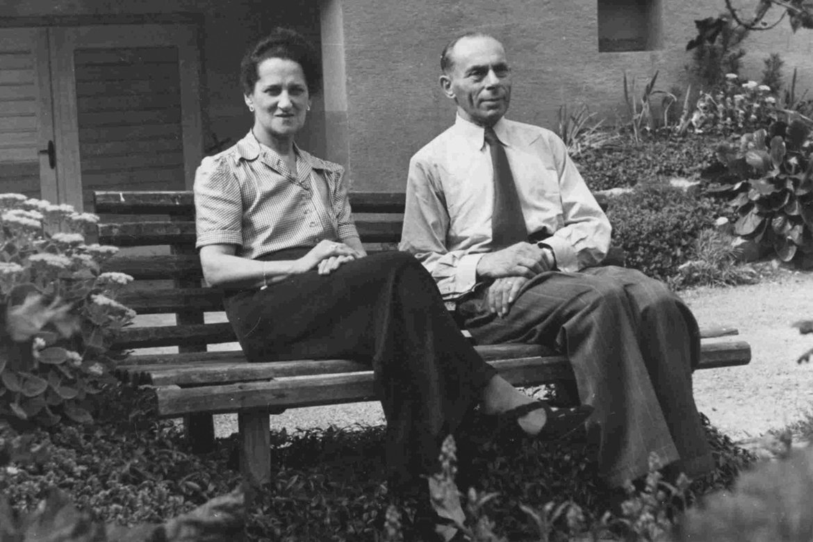 Schwarz-Weiß Fotografie: Karoline Krakauer und Max Krakauer rechts, sitzen auf einer Bank vor einem Haus